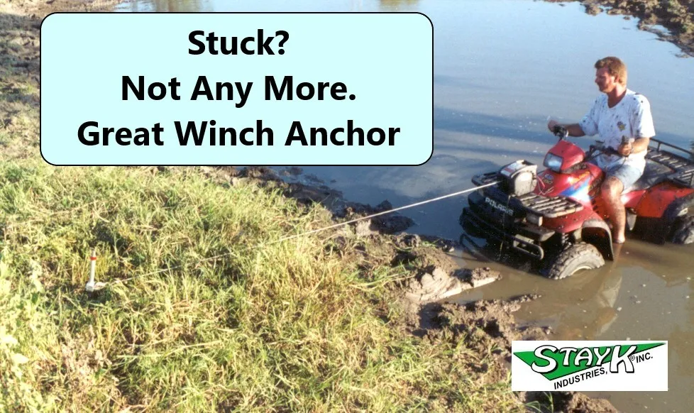 A man on an ATV pulls a winch anchor from muddy ground. Text promotes the winch anchor as a solution for getting unstuck.
