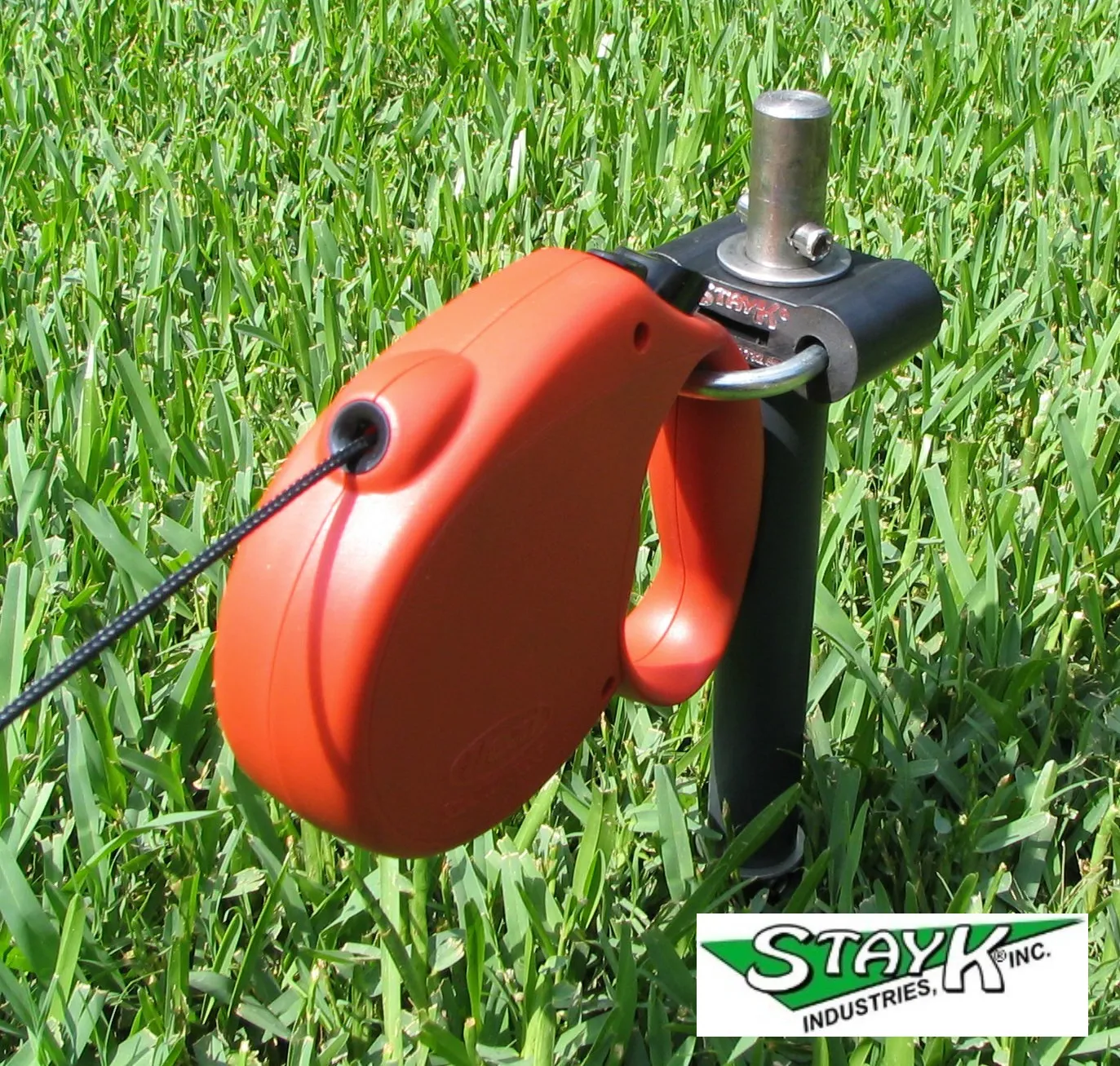 Retractable measuring tape with a bright orange casing resting on green grass. Used for precise distance measurements in outdoor settings.