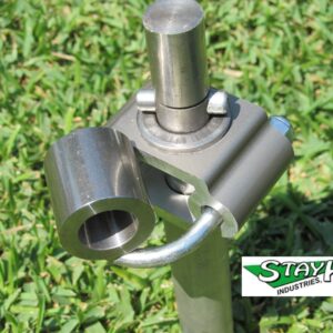 Metal bracket connector with a cylindrical attachment, set against green grass. Relevant for showcasing StayK Industries' innovative hardware solutions.
