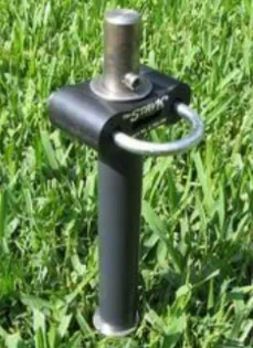 Heavy-duty ground anchor designed for securing equipment or tents, featuring a steel rod and loop for easy attachment, set in grass.